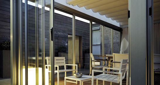 Eine Terrassenüberdachung in Leipzig mit Glasschiebewänden und einem Lamellendach. 