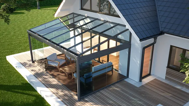 Eine Terrassenüberdachung wurde als Wintergarten an einem Haus angebaut. Im Wintergarten steht eine Sofaecke. 